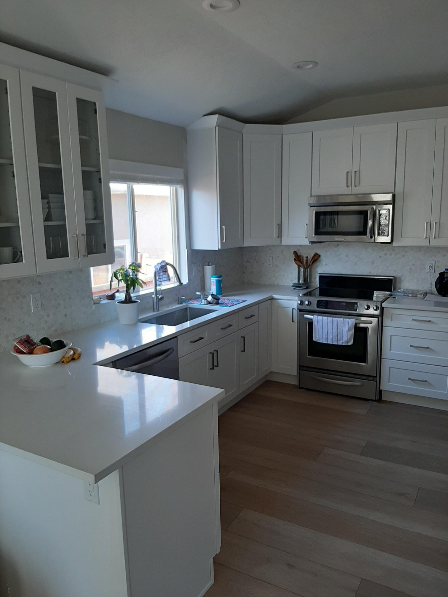 Finished U-shaped white kitchen with quartz counters and a hexagon marble backsplash